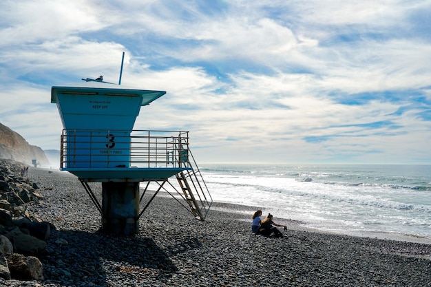 A beach scene with a lifeguard tower and a beach hut in the background.