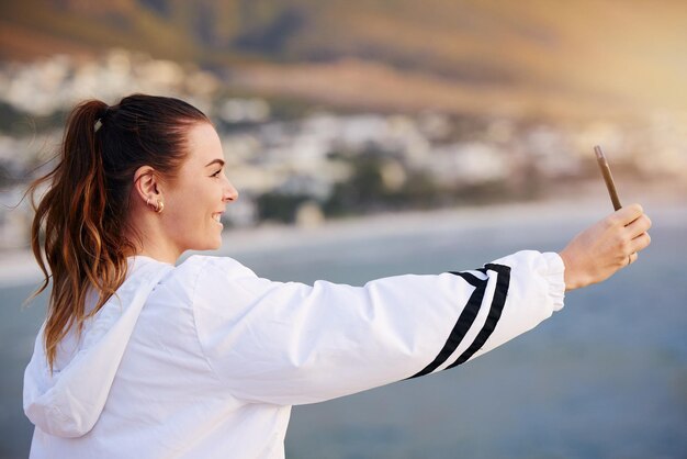 Beach selfie happy and woman with a phone for video call communication and social media update on holiday in Bali Travel influencer smile and girl with mobile photo on an ocean vacation in summer