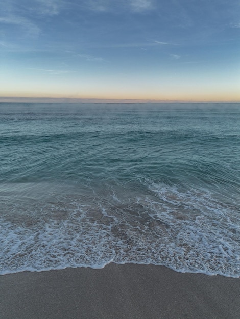 Beach shore wave background with the sunrise on the horizon