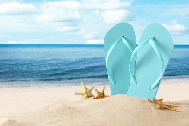 Пляжные тапочки и морские звезды на песчаном пляже у моря Летние каникулы