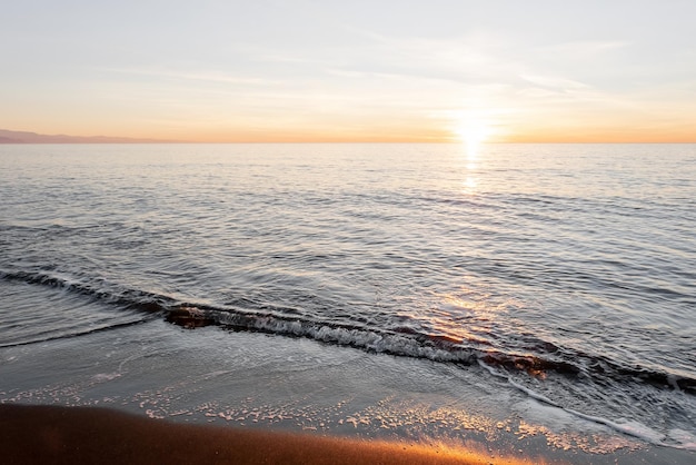 Beach Sunset Black magnetite sand and sea waves copper highlights on sand blurred background with selective focus