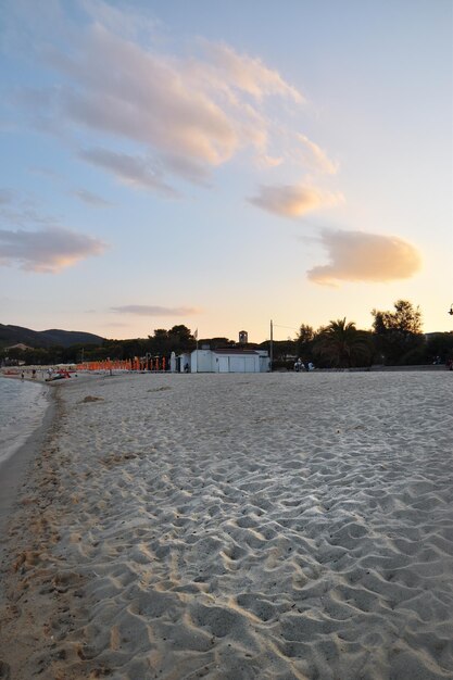 A beach at sunset with a building in the background