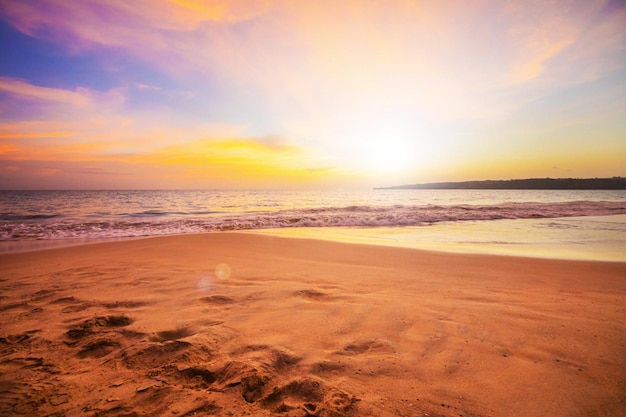 A beach at sunset with a colorful sky and the water in the background