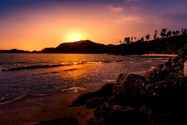 A beach at sunset with a mountain in the background