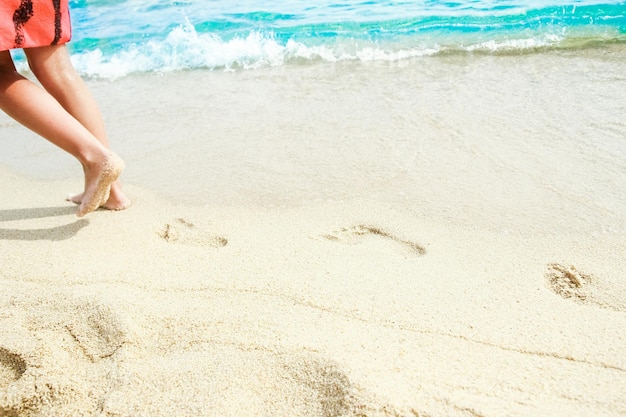 A Beach travel woman relaxing walking on a sandy beach leaving footprints in the sand Close up detail of female feet on golden sand at a beach in Greece Background