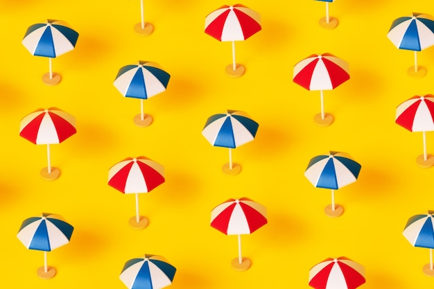 Photo beach umbrellas pattern over yellow background, summer vacation concept