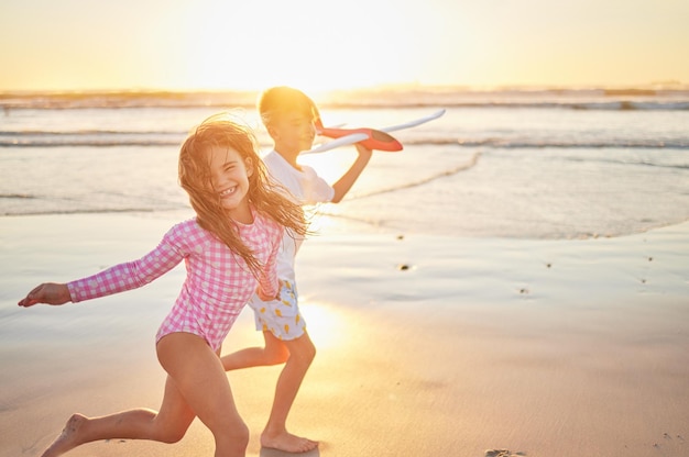 Beach vacation and children running with airplane toy for fun activity while on tropical summer vacation by the sea at sunset Sibling boy and girl or sister and brother enjoying a trip in maldives