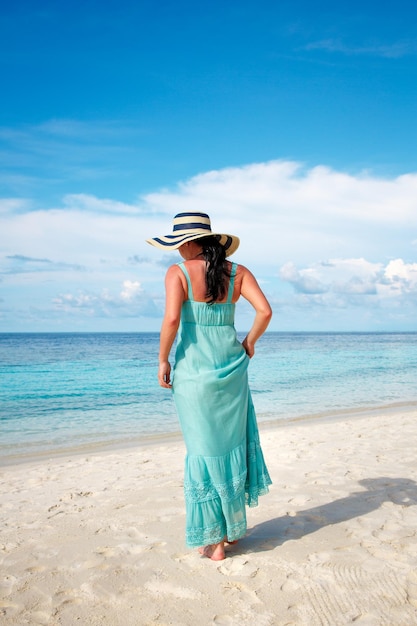 Beach vacation. Girl walking along a tropical beach in the Maldives.