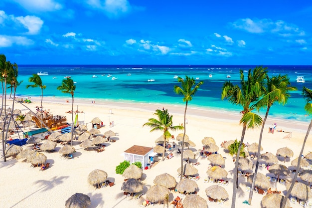 Beach vacation and travel background. Aerial drone view of beautiful atlantic tropical beach with straw umbrellas and palms. Bavaro beach, Punta Cana, Dominican Republic.