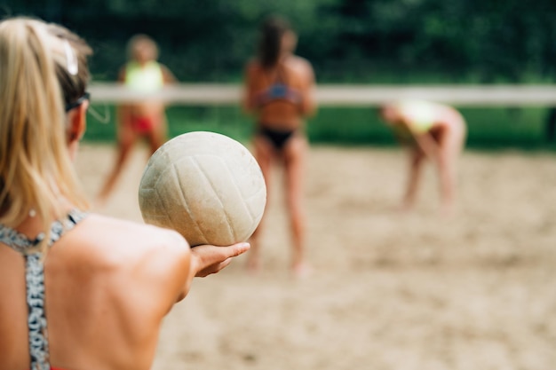 Foto giocatore femminile di beach volley che serve la palla