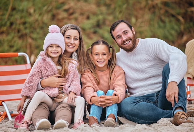 Beach winter and portrait of kids with parents sit on sand on holiday picnic Mom dad and children relax at ocean in Australia Freedom fun and vacation happy man and woman with girl kids at sea