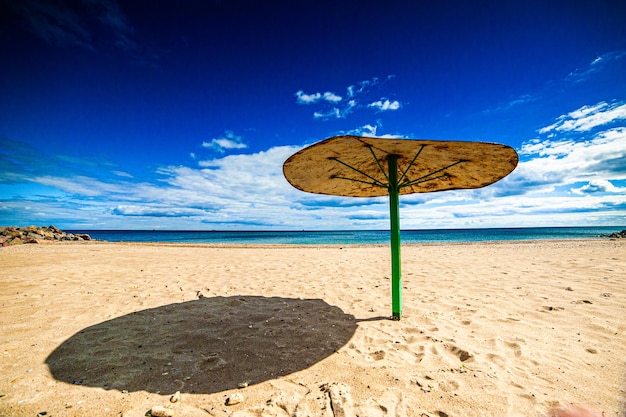 A beach with a blue sky and a green umbrella on it