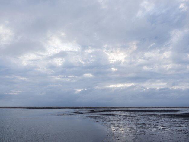 beach with bright sun shining through the clouds at sunset time