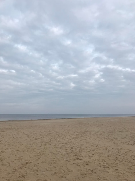 A beach with a cloudy sky and a beach with a man standing on it.