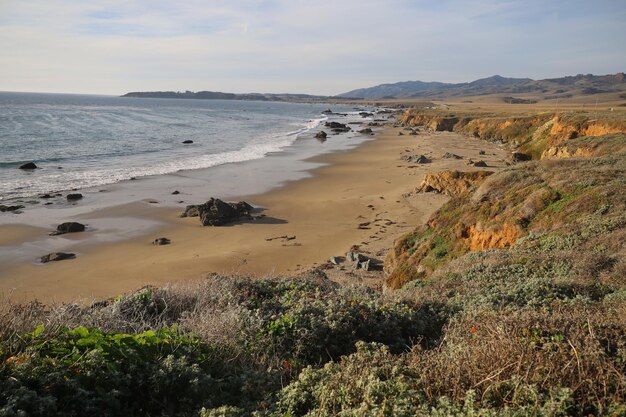 a beach with a house on the side and a beach in the background