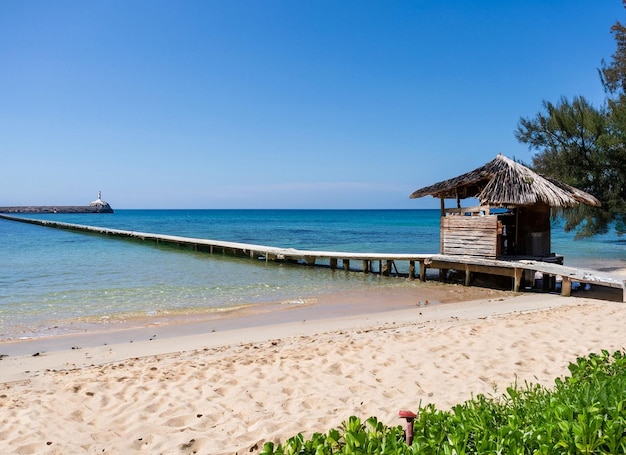 A beach with a hut on it and a boat in the background