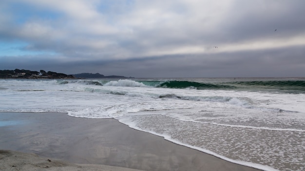 Photo beach with ocean waves in a stormy sunset