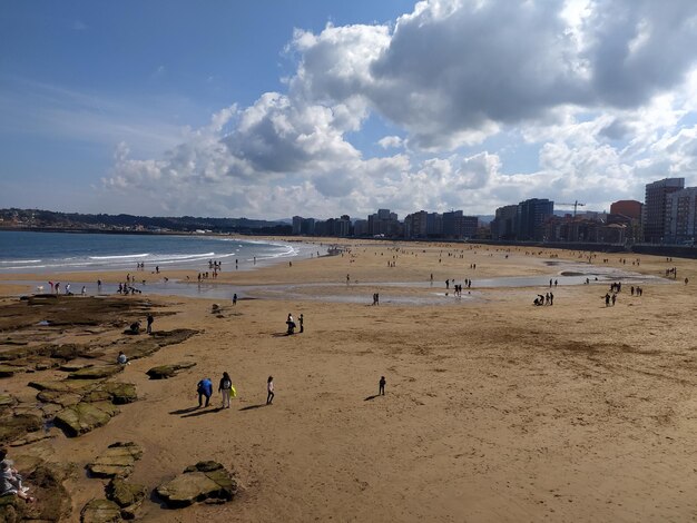 Photo a beach with people on it and a sky with clouds in the background