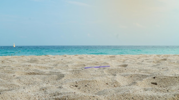 Foto una spiaggia con una cannuccia viola nella sabbia