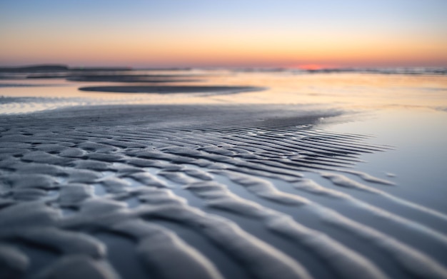 Photo a beach with ripples and the sky at sunset