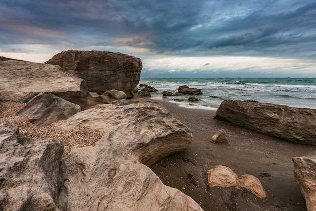 A beach with rocks and a cloudy sky