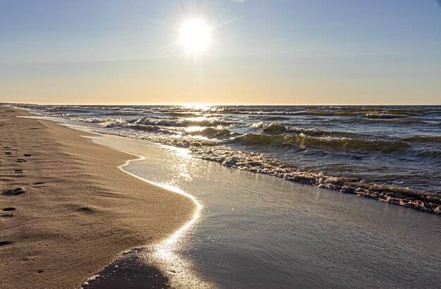 A beach with the sun setting over the water