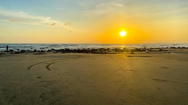 Una spiaggia con un tramonto sullo sfondo