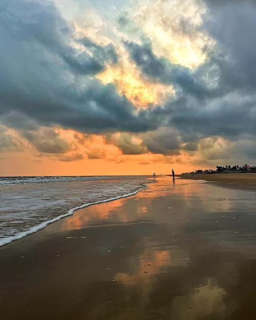 Foto una spiaggia con un tramonto e una persona in piedi sulla sabbia