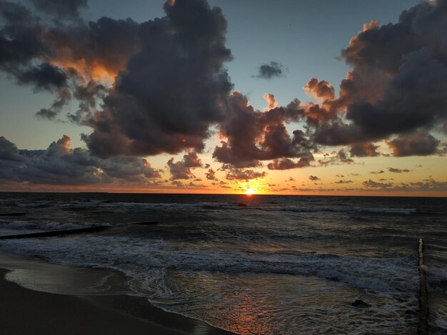 A beach with a sunset and the sun setting behind it