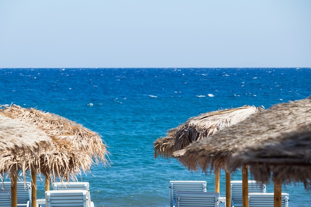 Beach with umbrellas and deck chairs by the sea in Santorini