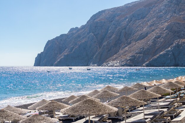 Photo beach with umbrellas and deck chairs by the sea in santorini