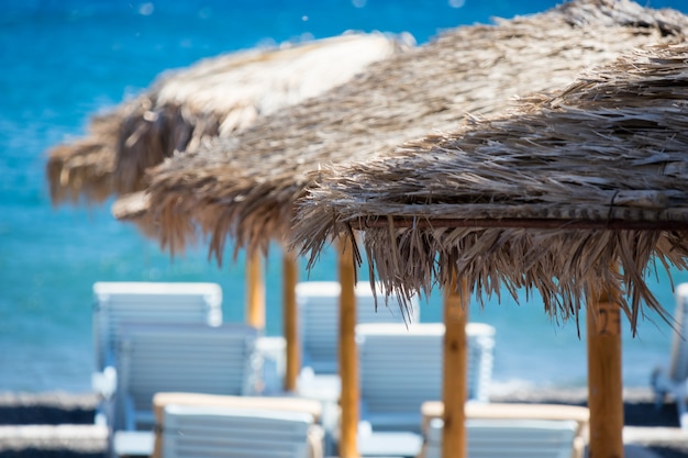 Photo beach with umbrellas and deck chairs in santorini