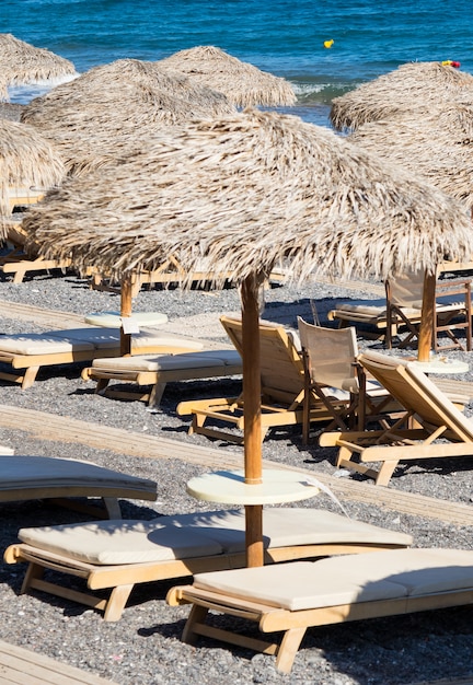 Beach with umbrellas and deck chairs in Santorini