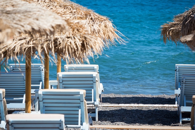 Beach with umbrellas and deck chairs in Santorini