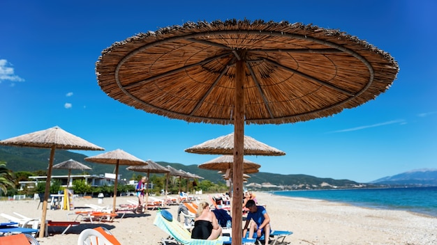 Beach with umbrellas, sunbeds and resting people, Olympiada, Greece