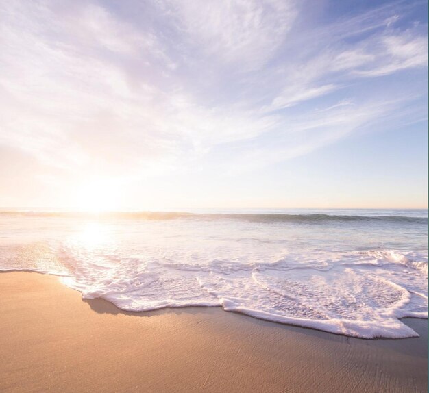 Photo a beach with a wave breaking on it and the sun is setting