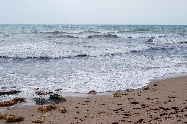 Photo a beach with waves and rocks on it