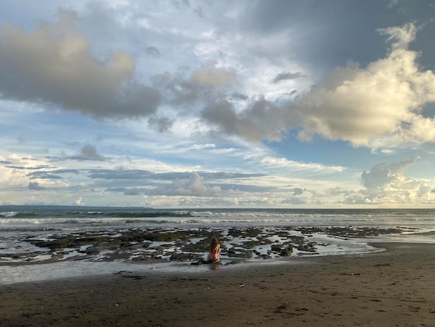 A beach with a woman on it and a man on the sand.