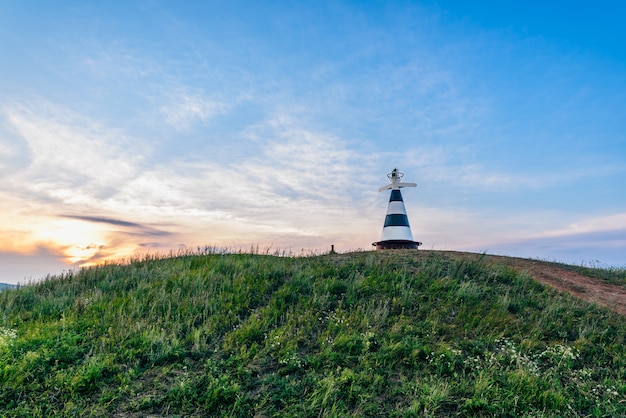 Faro con il puntatore sulla collina nella luce del tramonto