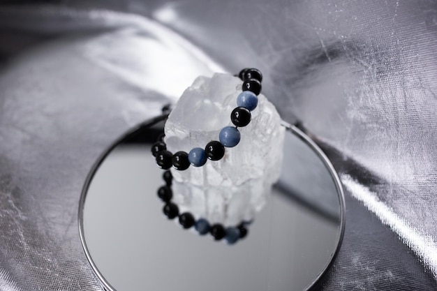 Beads from multicolored natural stones lie on a snowwhite stone topaz and quartz on a silver background