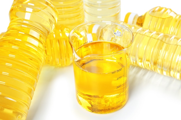 Beaker and bottles with cooking oil on white surface