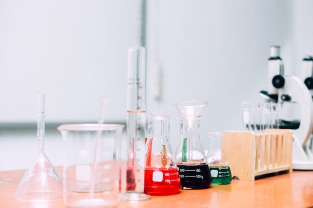 Beakers, microscopes and various laboratory equipment on wooden table