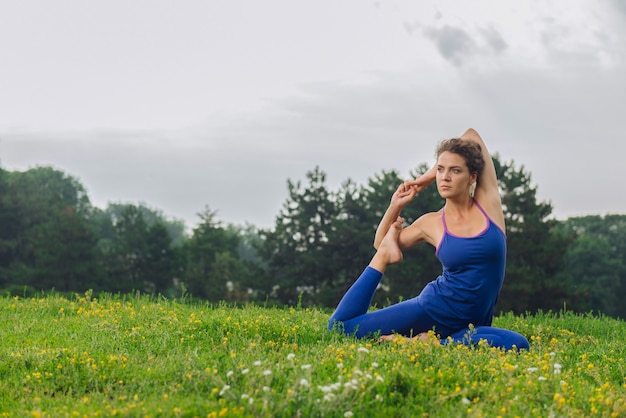 Photo beaming curly woman feeling free and calm while improving her flexibility with stretching