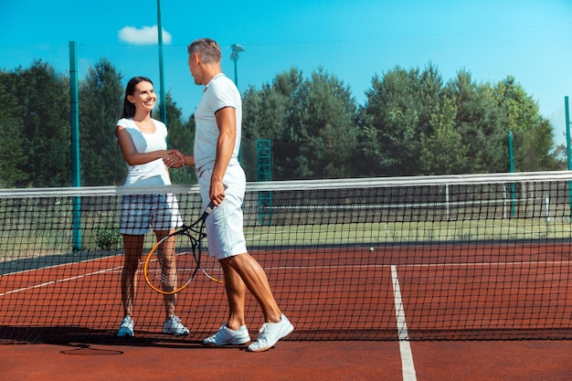 Beaming wife feeling happy after playing tennis with husband