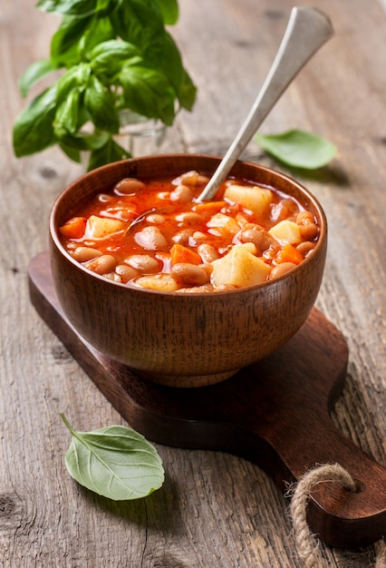 Bean soup in a wooden bowl on the old wooden background