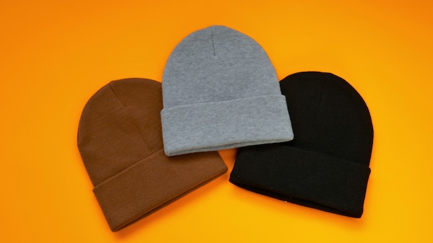 Photo beanie hats set on a bright orange background gray black and brown knitted hats fashion hats