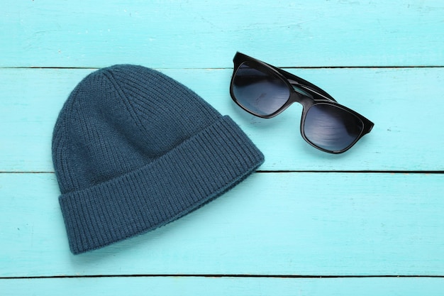 Beanie and sunglasses on a blue wooden background