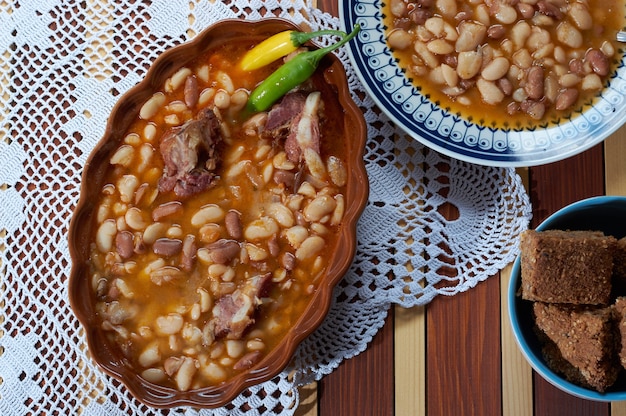 Fagioli con maiale affumicato su piatto piano con pane di spelta