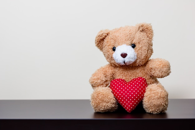 Bear doll and red heart on wooden table