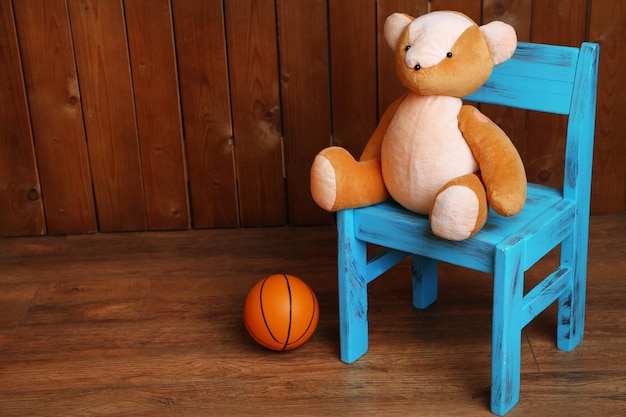 Bear toy on chair on wooden background